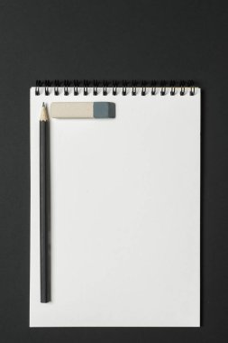 Keskinleştirilmiş bir kalem ve gri bir silgi eşliğinde karanlık bir yüzeye uzanan boş bir sarmal defter. Kurulum gelişmekte olan sanatçıları yaratıcılıklarını ve fikirlerini serbest bırakmaya davet ediyor..