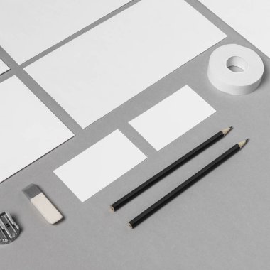 Düzenli bir çalışma alanı boş kağıtlar, siyah kalemler, bir silgi, bir zımba ve gri bir yüzeye düzgünce yerleştirilmiş bir bant içerir. Beyin fırtınası ve sanatsal yaratım için ideal..