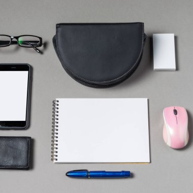 Gri bir yüzeye düzgün yerleştirilmiş çeşitli araçlar verimliliği destekler. Ögeler arasında bir defter, akıllı telefon, gözlük, kalem, fare ve cüzdan, odaklanmış görevler için minimalist bir çalışma alanı oluşturma.