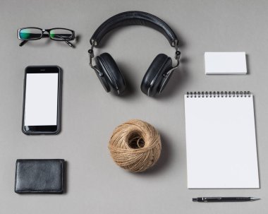 Minimalist bir çalışma alanı dikkatle düzenlenir kulaklıklar, akıllı telefon, ve bir not defteri, ilham ve üretkenliği davet eder..