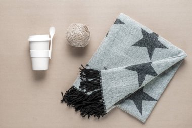 Yumuşak bir yıldız desenli battaniye sıcak bir içecek, sicim topu ve kaşık dolu bir yüzey üzerinde bir fincan yanında uzanır ve öğleden sonra inzivaya çekilmek için mükemmel bir ortam yaratır..