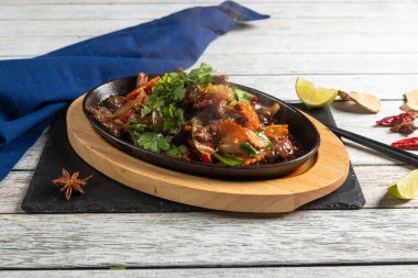 Lezzetli bir tabak cızırtılı yemek vitrinleri sulu malzemeler, renkli baharatlar ve taze otlar, yakınlardaki kireç ve baharatlarla güzel bir şekilde sade ahşap bir masa üzerinde dizilmiş..