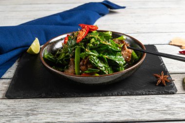 Canlı bir yemek sergisi sotelenmiş yeşiller ve limon dilimleri ve dokulu bir tabakta renkli baharatlarla süslenmiş taze et.. 