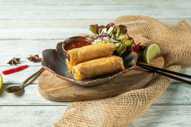 Taze yeşillikler, bol bir sos ve lezzeti arttırmak için limon dilimleri eşliğinde taşralı ahşap bir tabağın üzerinde harika bir düzenleme var..