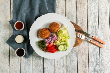 Lezzetli bir vejetaryen tabağı kırsal bir ahşap masanın üzerinde duruyor..