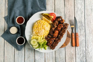 Taze ızgara kebapların tadını çıkarın. Yanında da yumuşak pirinç. Salatalık, domates ve limonla süslenmiş bu canlı yemek günün her saatinde sağlıklı yemek için mükemmeldir..