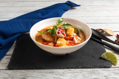 Deniz ürünleri güveciyle dolu güzel bir kase servis tahtasının üzerinde oturur..