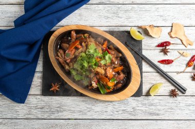 Lezzetli et parçaları ve renkli sebzeler ahşap bir tabakta cızırdar, buhar yükselir, taze otlar, limon ve baharatlarla süslenir, duyuları keyiflendirmeye hazırdır..