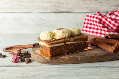 A beautifully crafted layered cake rests on a wooden board, showcasing creamy frosting and warm spices. Cinnamon sticks and coffee beans enhance the cozy atmosphere, inviting indulgence.