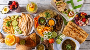 Neşeli bir toplantı, taze meyve, lezzetli sarmalar, baharatlar ve canlı içecekler de dahil olmak üzere bir dizi lezzetli yemek sergiliyor. Arkadaşlar bu hayat dolu yemek deneyiminde kahkahaları ve güzel yemekleri paylaşırlar..