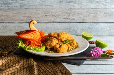 Çok güzel düzenlenmiş bir tabakta rengarenk sebzeler, limon kamaları ve sanatsal süslerle tamamlanmış kızarmış balıklar bir mutfak başyapıtı yaratıyor..