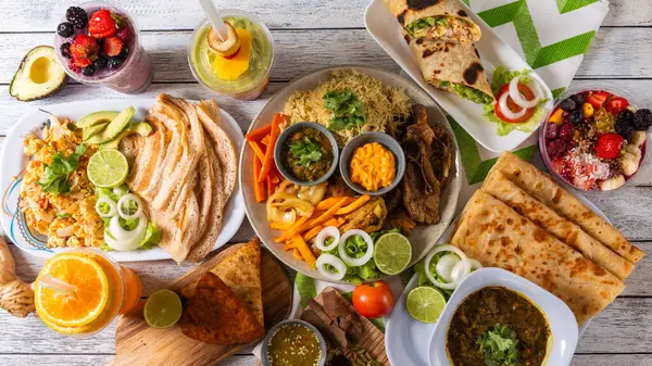 Neşeli bir toplantı, taze meyve, lezzetli sarmalar, baharatlar ve canlı içecekler de dahil olmak üzere bir dizi lezzetli yemek sergiliyor. Arkadaşlar bu hayat dolu yemek deneyiminde kahkahaları ve güzel yemekleri paylaşırlar..