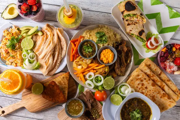 Kırsal ahşap bir masada çok güzel düzenlenmiş çeşitli yemekler. Renkli tabaklar canlı salatalar, lezzetli etler ve ferahlatıcı içecekler içerir. Arkadaşlarla anları paylaşmak için mükemmel..