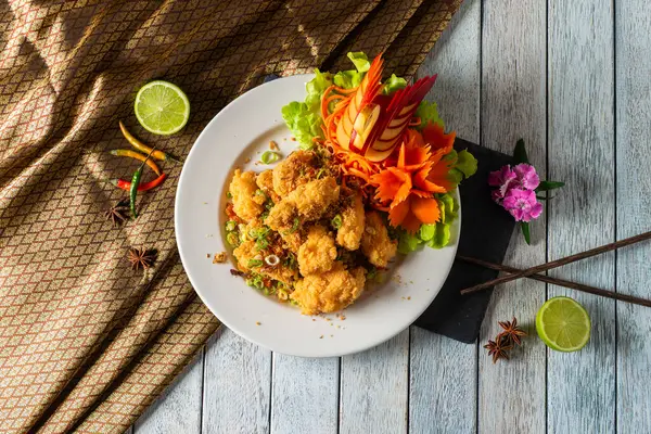 Canlı bir tabak kızarmış karides, marul ve sanatsal sebze oymaları da dahil renkli süslemelerle güzelce düzenlenir..
