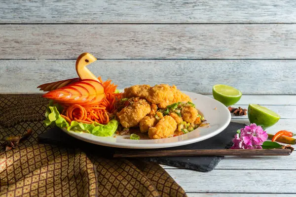 Çok güzel düzenlenmiş bir tabakta rengarenk sebzeler, limon kamaları ve sanatsal süslerle tamamlanmış kızarmış balıklar bir mutfak başyapıtı yaratıyor..