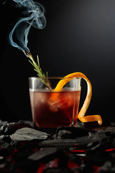 アイス オレンジピール ローズマリーなどの昔ながらのカクテル 暗い背景にローズマリーの燃えるような小枝とウィスキー — ストック写真