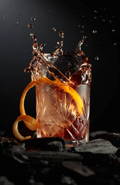 氷の部分はカクテルでガラスに落ちます 暗い背景に氷とオレンジの皮を持つカクテル — ストック写真