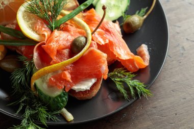 Somonlu sandviç, krem peynir, dereotu, salatalık, kapari, yeşil soğan ve limon..