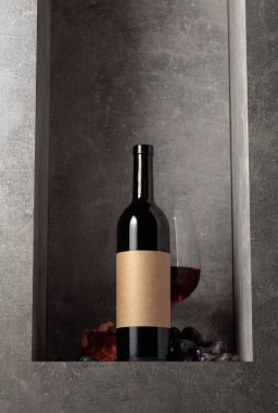 Mavi üzümlü bir şişe ve bir bardak kırmızı şarap. Şişede eski boş etiket var. Boşluğu kopyala.