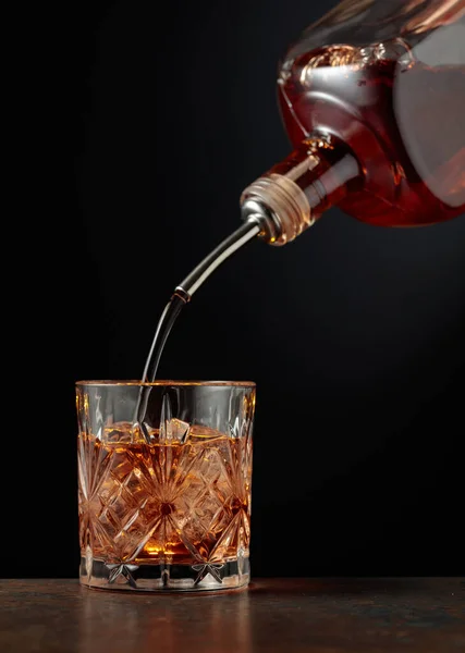 ウイスキーは瓶から氷の入ったガラスに注がれる — ストック写真