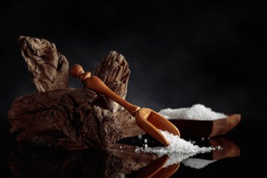 Siyah yansıtıcı arka planda eski bir engel olan deniz tuzu. Tema konsepti doğal malzemeler ve spa. Boşluğu kopyala.