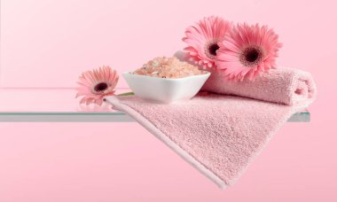 Pembe tuz, çiçek ve havluyla spa kompozisyonu.