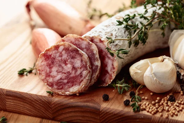 Traditional dry-cured sausage with thyme, garlic, onion, and spices. Dry-cured sausage on a wooden table.