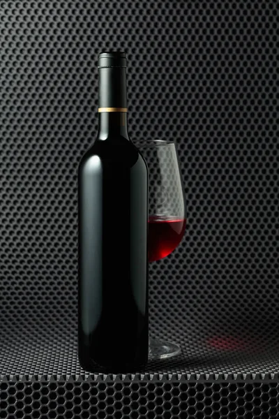 灰色蜂窝背景下的红葡萄酒瓶和酒杯 — 图库照片
