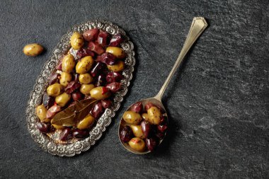 Spicy olives on a black stone table. Top view.