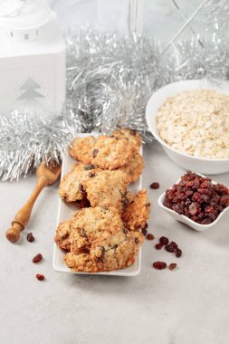 Ev yapımı yulaf ezmeli kurabiye ve Noel süslemeleri olan bir masada kuru üzüm..