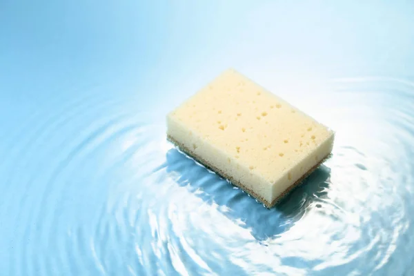 New and clean sponge falls into the water forming waves. Clean concept. Copy space.