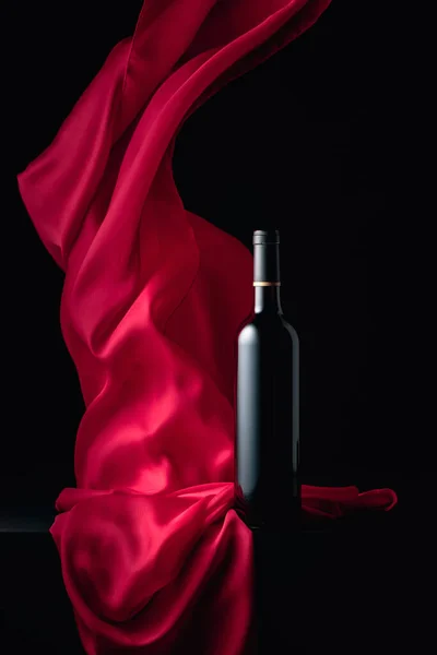Siyah Arka Planda Kırmızı Kanat Çırpan Kumaşlı Bir Şişe Kırmızı — Stok fotoğraf
