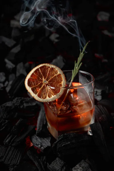 乾燥オレンジスライス ローズマリーと古いスタイルのカクテル 木炭を燃焼させる背景に煙のローズマリーと美しい渦を持つウイスキー — ストック写真