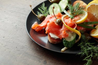 Somonlu sandviç, krem peynir, dereotu, salatalık, kapari, yeşil soğan ve limon..