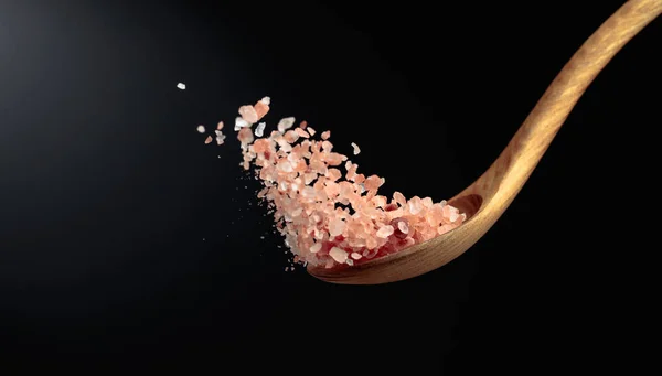 ピンクのヒマラヤ塩は木製のスプーンで注ぎます 暗い背景にヒマラヤ塩 スペースのコピー — ストック写真