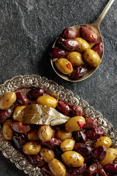 Spicy olives on a black stone table. Top view.