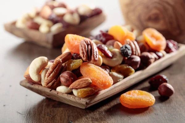 Mix of nuts and dried fruits on an old wooden table. Presented apricots, raisins, walnuts, hazelnuts, cashews, pecans, and almonds.