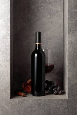 Siyah arka planda kırmızı kanat çırpan kumaşlı bir şişe kırmızı şarap. Boşluğu kopyala.