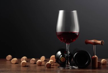 Ahşap bir masada kırmızı şarap ve şarap mantarları. Boşluğu kopyala.