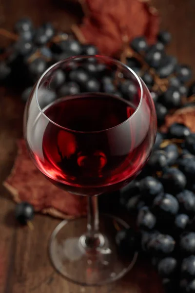 红酒和蓝色葡萄放在一张旧木桌上 有选择的重点 — 图库照片