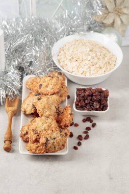 Ev yapımı yulaf ezmeli kurabiye ve Noel süslemeleri olan bir masada kuru üzüm..