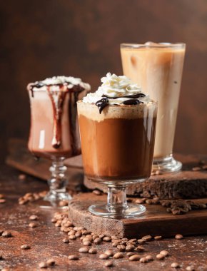 Kahverengi arka planda kremalı kahve ve çikolata içecekler..