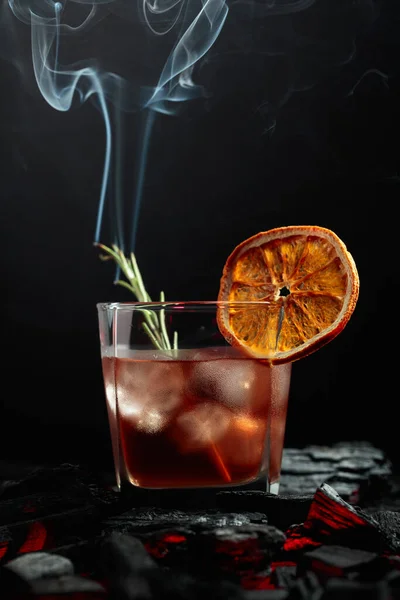 乾燥オレンジスライス ローズマリーと古いスタイルのカクテル 黒を背景にローズマリーと煙の美しい渦 — ストック写真
