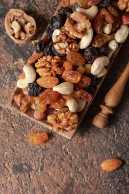 Kahverengi bir arka planda fındık ve kuru üzüm karışımı. Sunulan kuru üzüm, ceviz, fındık, fındık, ceviz, ceviz ve badem. Üst görünüm.