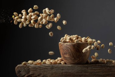 Uçan tuzlu şam fıstığı. Tahta bir kasede kurutulmuş fındık. Boşluğu kopyala.