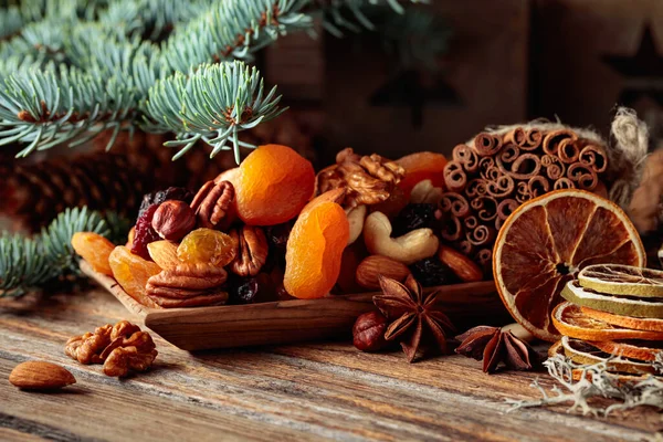 stock image Dried fruits and nuts on an old wooden table. Christmas still-life with dried citrus, apricots, raisins, various nuts, cinnamon sticks, and anise.