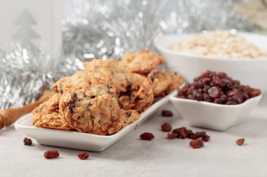 Ev yapımı yulaf ezmeli kurabiye ve Noel süslemeleri olan bir masada kuru üzüm..