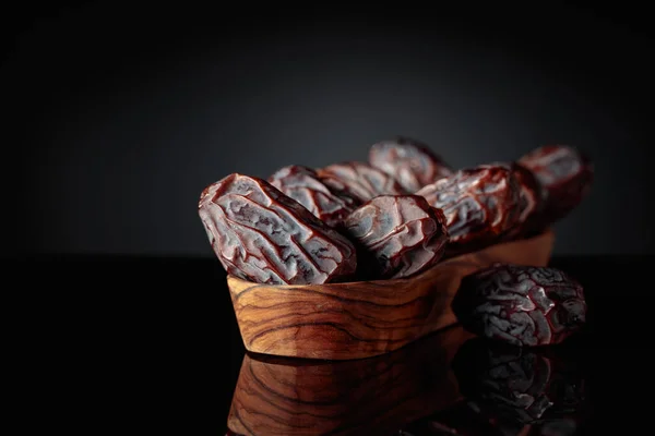 Rohe Reife Dattelfrüchte Auf Einem Hölzernen Teller Auf Schwarzem Hintergrund — Stockfoto