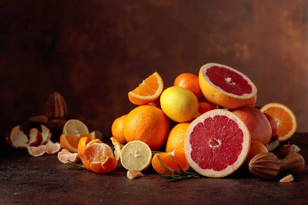Citrus fruits on a old brown table. Presented are oranges, grapefruits, lemons, and tangerines. Copy space.
