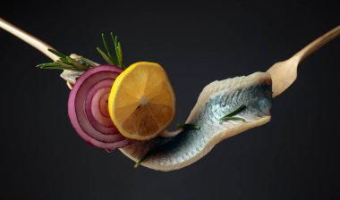 Limonlu ringa fileto, kırmızı soğan ve siyah arka planda biberiye..